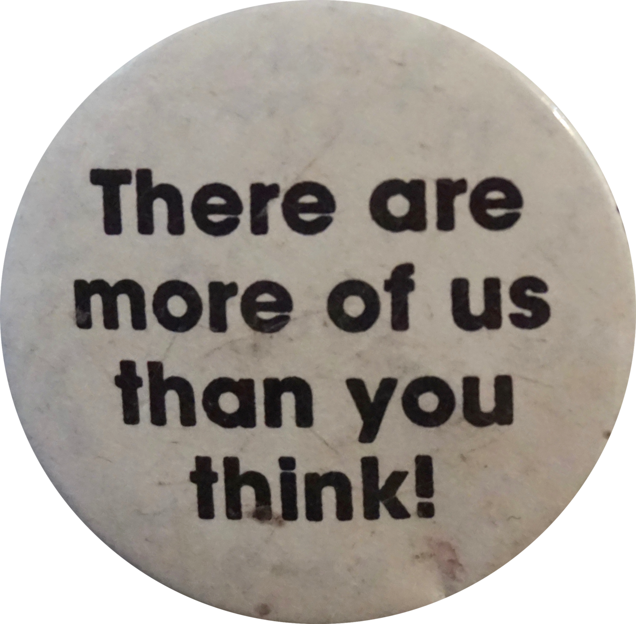 Image Description: A photo of a worn circular pin that says 'There are more of us than you think!' in bold black text on white background.